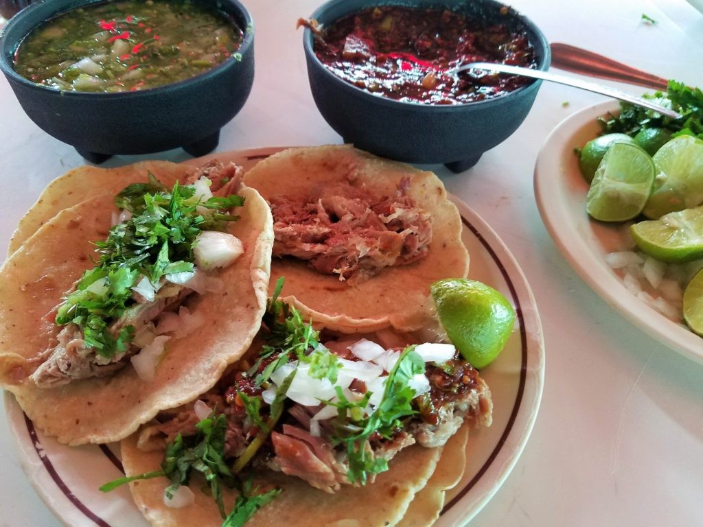 Barbacoa Lamb on tacos with salsas, onions and cilantro.
