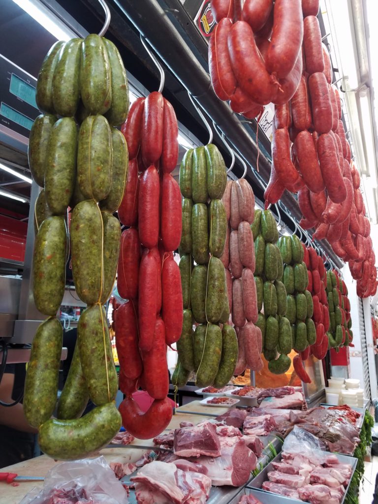 Meat vendor with red and green chorizo sausages at Mercado La Cruz