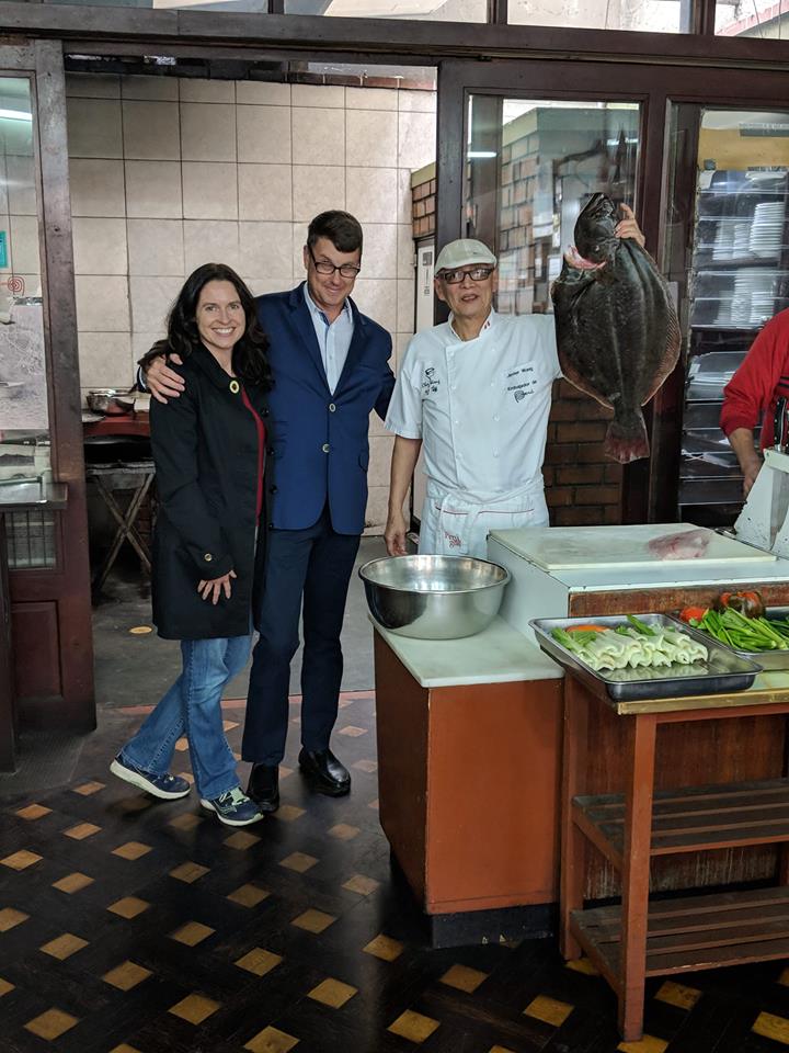 Tiffany and Tom posing with Cheaz Wong holding a turbot at his restaurant in Lima, Peru