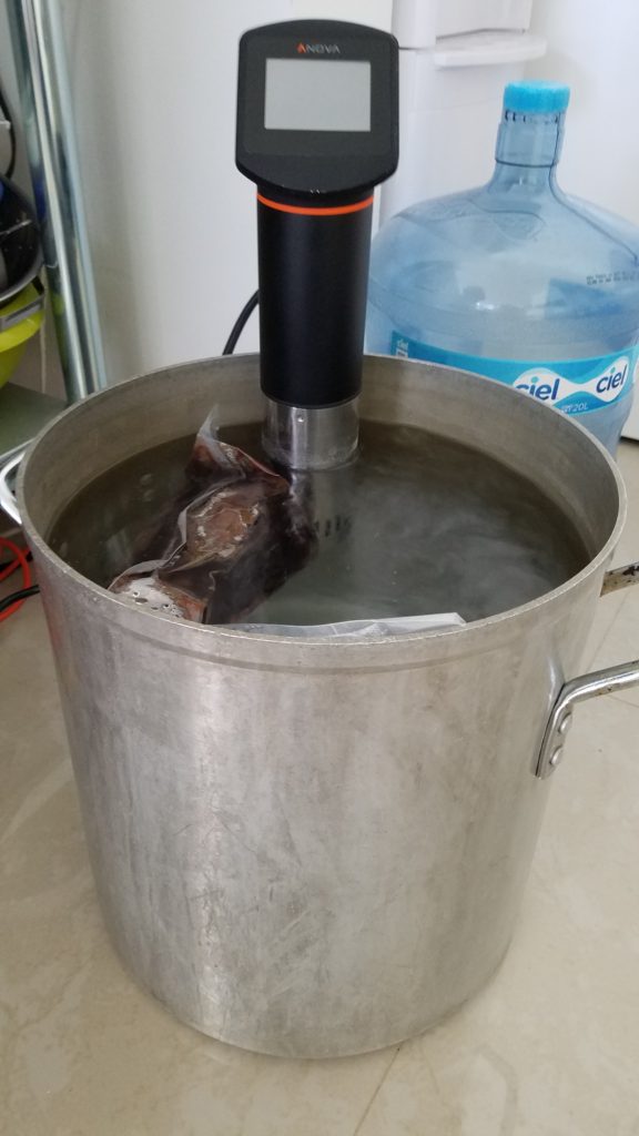 Sous vide circulator with tongue cooking in pot.