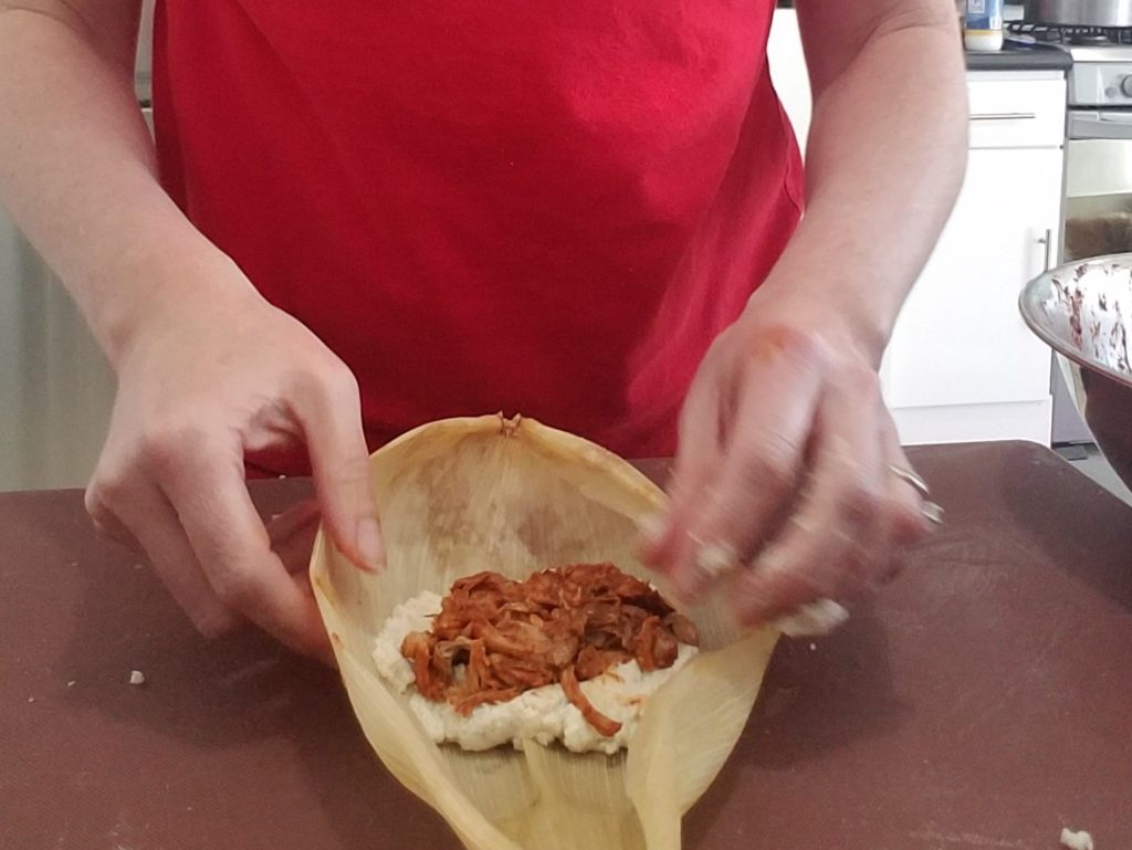 Corn husk with masa and pork for tamale making