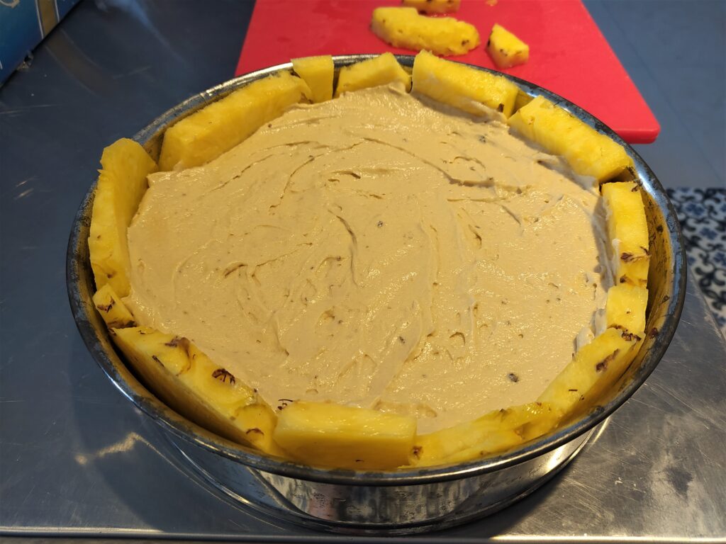 Fruit is arranged on the bottom and sides of pan for a pineapple upside down cake. Batter is poured into 2/3 of the cake pan and spread evenly to the sides. Fruit is arranged on the bottom and sides of pan for a pineapple upside down cake. Batter is poured into 2/3 of the cake pan and spread evenly to the sides.