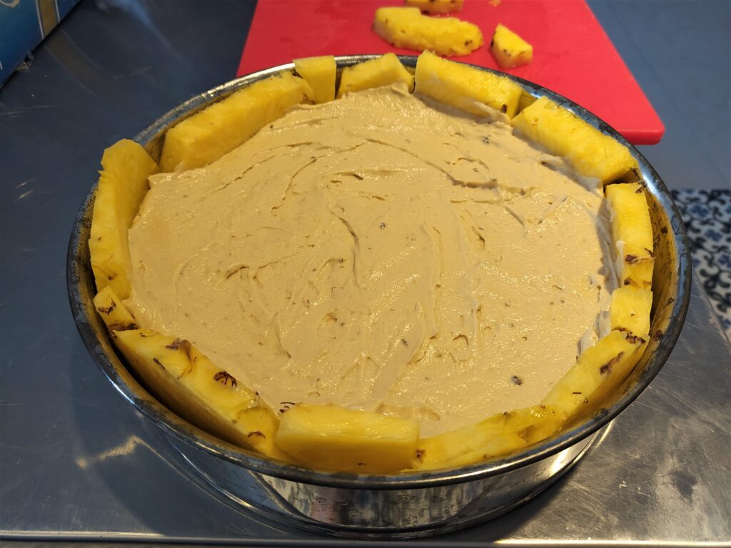 Fruit is arranged on the bottom and sides of pan for a pineapple upside down cake. Batter is poured into 2/3 of the cake pan and spread evenly to the sides. 